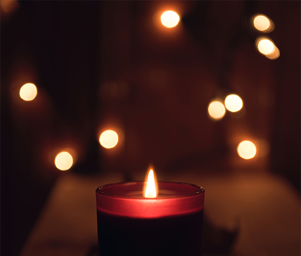 Lit-candle-with-fairy-lights-in-background